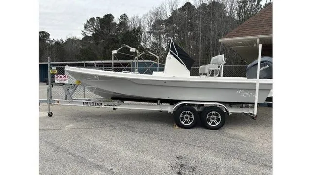 The Image of 2025 Bay Rider 219 Bay boat on trailer, parked outdoors near trees and building. - 1