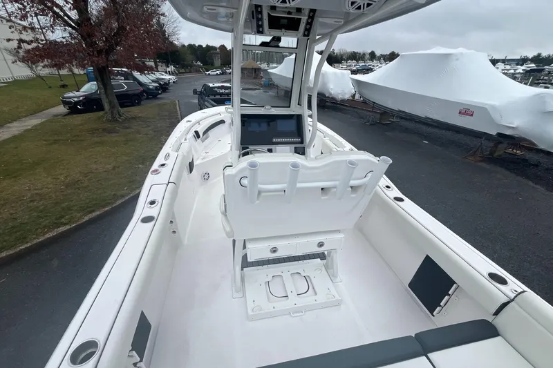 Slide: The Image of 2024 Tidewater 232 LXF boat interior with helm and seating, parked outdoors. - 14