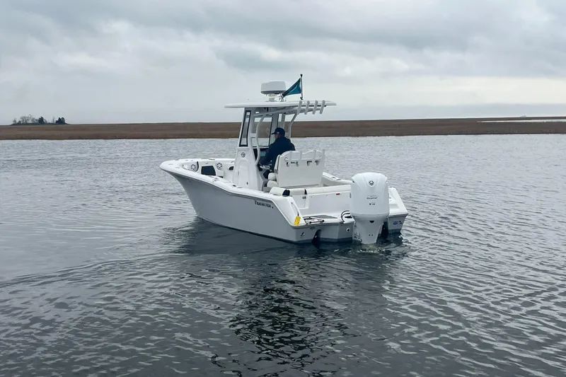 Slide: The Image of 2024 Tidewater 232 LXF boat cruising on calm waters under cloudy skies. - 6