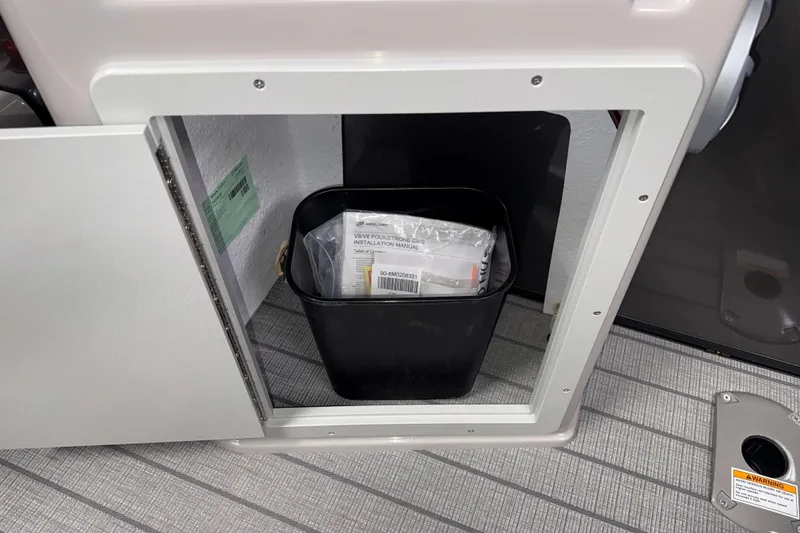 Slide: The Image of Open storage compartment in 2026 Sylvan L3 DLZ Bar with manual and trash bin. - 24