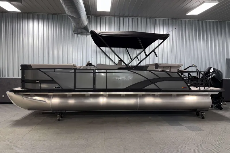 Slide: The Image of 2026 Sylvan L3 DLZ Bar pontoon boat in a showroom, featuring sleek design and canopy. - 29