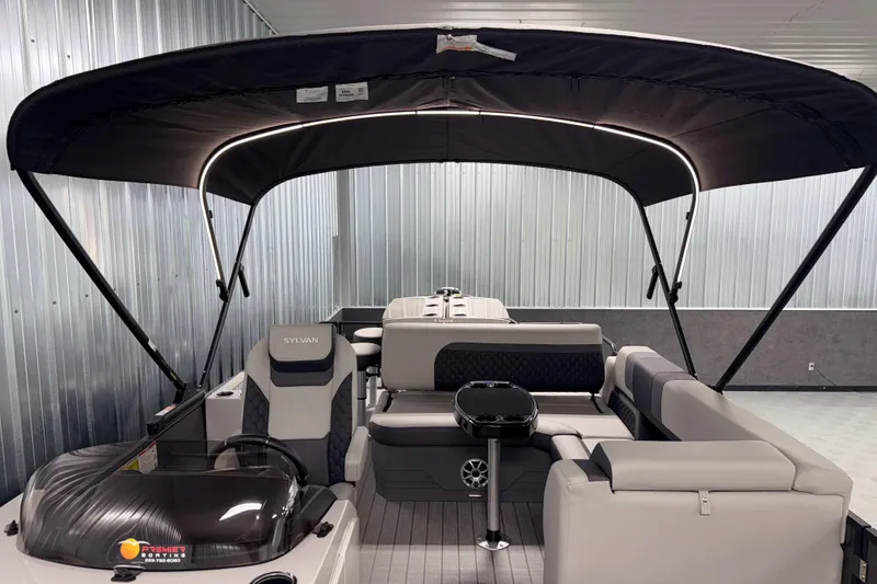 Slide: The Image of 2026 Sylvan L3 DLZ Bar pontoon boat interior with canopy in a showroom. - 8