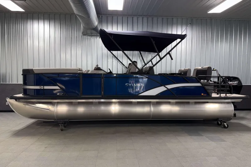 Slide: The Image of 2026 Sylvan L3 RLZ pontoon boat in a showroom with blue and silver design. - 33