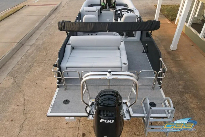 Slide: The Image of 2022 Bentley 243 Swingback pontoon boat with seating and outboard motor, docked on pavement. - 5