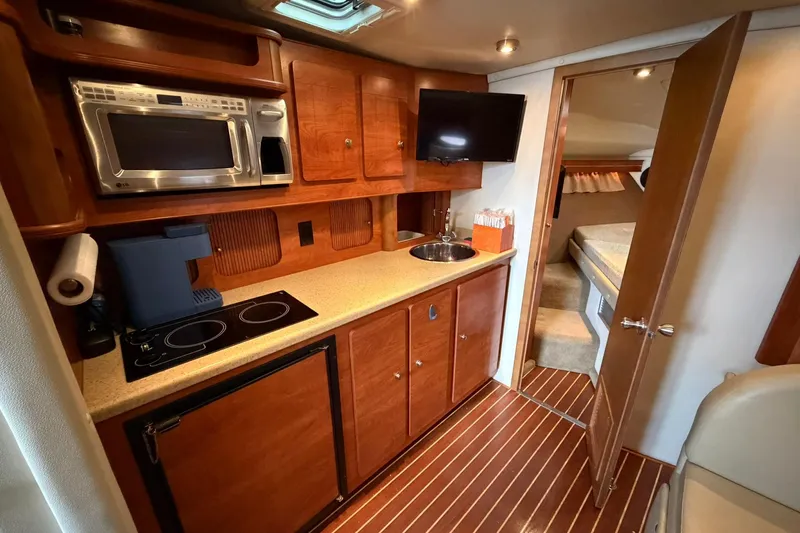 Slide: The Image of 2007 Rinker 370 Express Cruiser Hard Top interior with kitchenette and cozy cabin. - 17