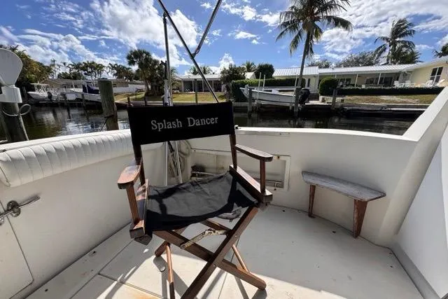 Slide: The Image of 1987 Carver 32 Aft Cabin Motor Yacht deck with "Splash Dancer" chair, docked by waterfront homes. - 18