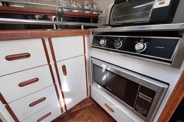 Slide: The Image of 1987 Carver 32 Aft Cabin Motor Yacht kitchen with stove, microwave, and wooden cabinets. - 41