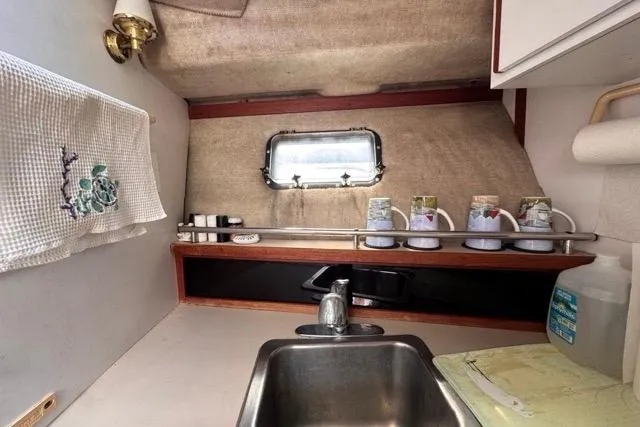 Slide: The Image of 1987 Carver 32 Aft Cabin Motor Yacht kitchen with sink, window, and storage shelves. - 42