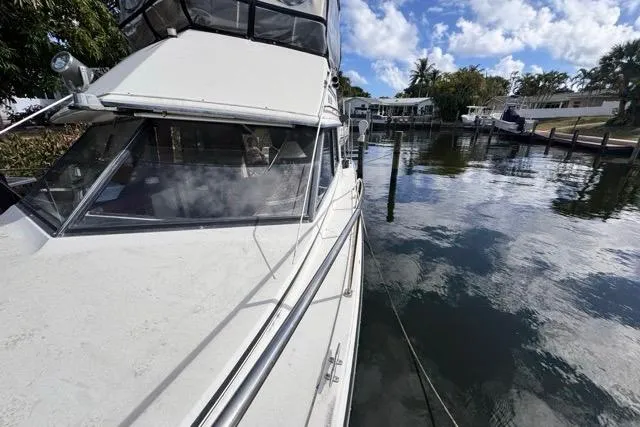 Slide: The Image of 1987 Carver 32 Aft Cabin Motor Yacht docked by a serene waterfront. - 69