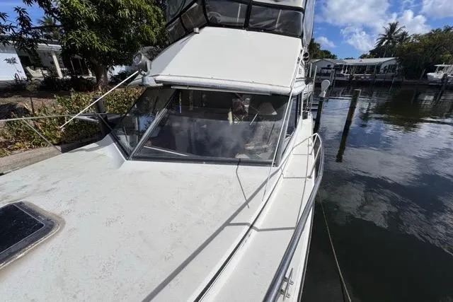 Slide: The Image of 1987 Carver 32 Aft Cabin Motor Yacht docked by a serene waterfront. - 70