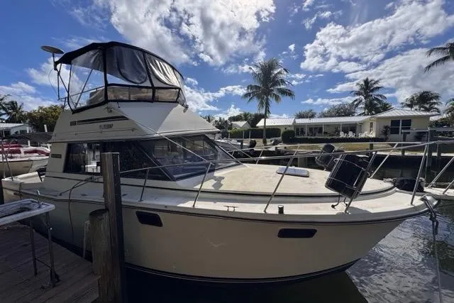 The Image of 1987 Carver 32 Aft Cabin Motor Yacht docked, with clear skies and palm trees in the background. - 1
