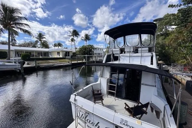 Slide: The Image of 1987 Carver 32 Aft Cabin Motor Yacht docked by waterfront homes under blue sky. - 10