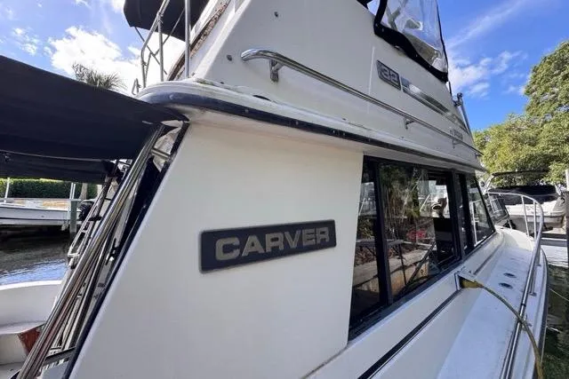 Slide: The Image of 1987 Carver 32 Aft Cabin Motor Yacht docked, showcasing sleek design and branding. - 15
