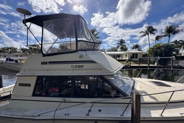 Slide: The Image of 1987 Carver 32 Aft Cabin Motor Yacht docked under a sunny sky with palm trees. - 16
