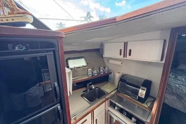 Slide: The Image of 1987 Carver 32 Aft Cabin Motor Yacht kitchen with sink, stove, and cabinets. - 47