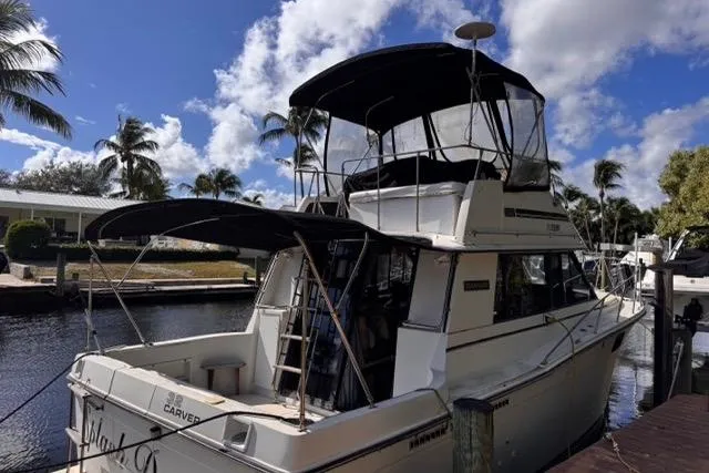 Slide: The Image of 1987 Carver 32 Aft Cabin Motor Yacht docked by palm trees under a blue sky. - 79