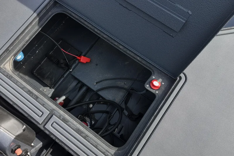Slide: The Image of Open storage compartment of 2026 Xpress X18DB boat with visible wiring and components. - 15