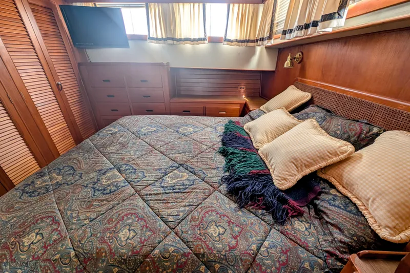 Slide: The Image of Cozy bedroom in 1988 Grand Banks 46 Classic yacht with patterned bedding and wooden cabinetry. - 30