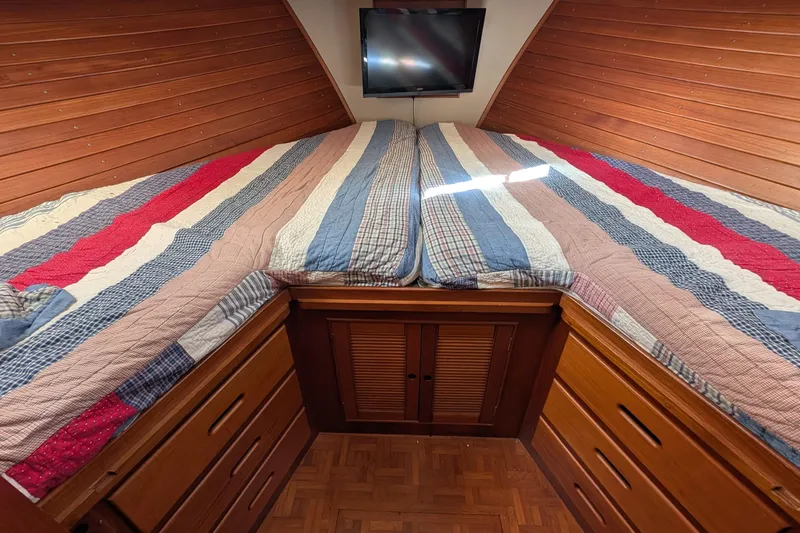 Slide: The Image of Cozy cabin bedroom in 1988 Grand Banks 46 Classic yacht with striped bedding and wood paneling. - 43