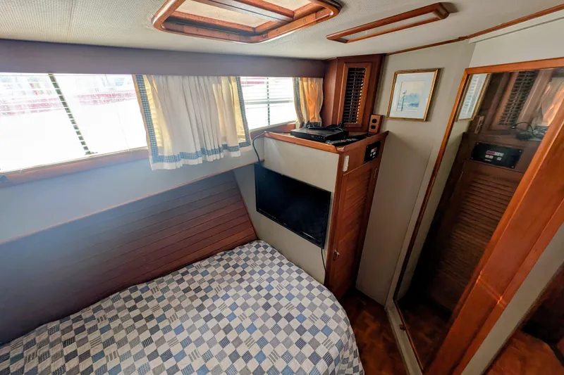 Slide: The Image of 1988 Grand Banks 46 Classic cabin with bed, window, and wooden interior. - 49