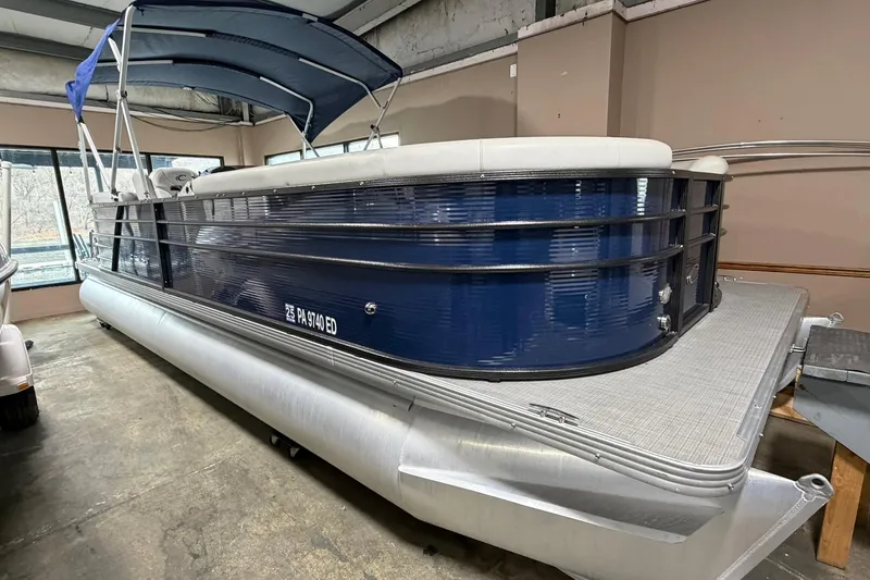 Slide: The Image of 2021 Crest Classic Platinum 240 SLC pontoon boat with blue exterior in indoor storage. - 0