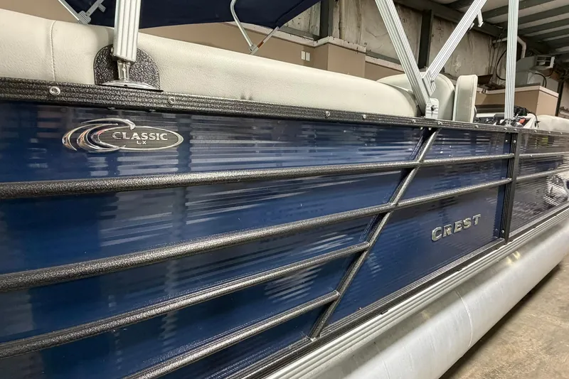Slide: The Image of 2021 Crest Classic Platinum 240 SLC pontoon boat with blue exterior and white seating. - 1