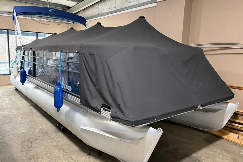 Slide: The Image of 2021 Crest Classic Platinum 240 SLC pontoon boat with black cover in storage. - 13