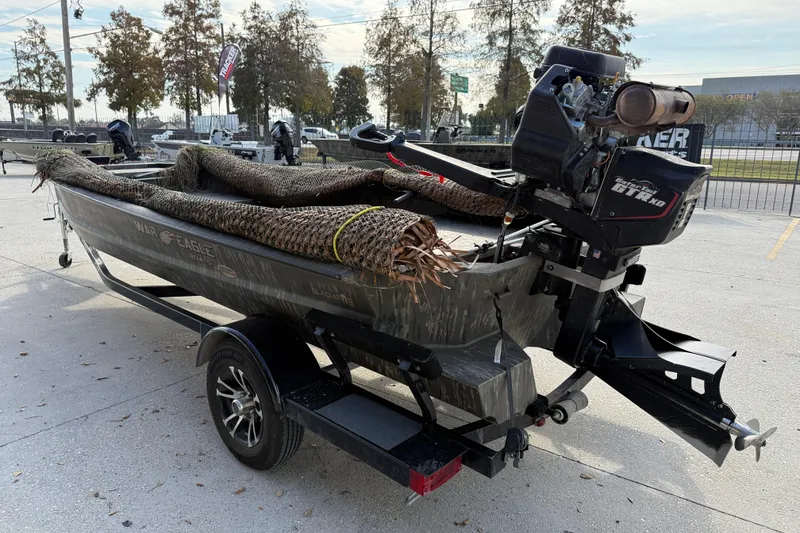 Slide: The Image of 2026 War Eagle 750 Gladiator boat on trailer, equipped with camouflage netting and outboard motor. - 5