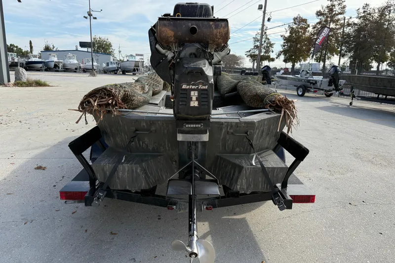 Slide: The Image of War Eagle 750 Gladiator 2026 boat with camo design and motor, parked outdoors. - 6