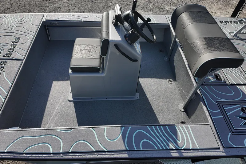 Slide: The Image of 2026 Xpress Skiff 185 boat with unique topographic design, parked outdoors. - 12