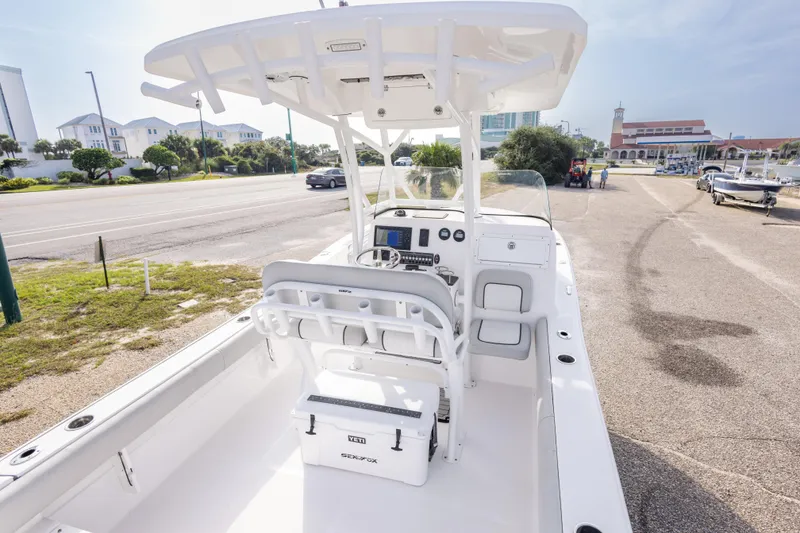 Slide: The Image of 2020 Sea Fox 249 Avenger boat interior with console and seating, parked near a coastal road. - 18