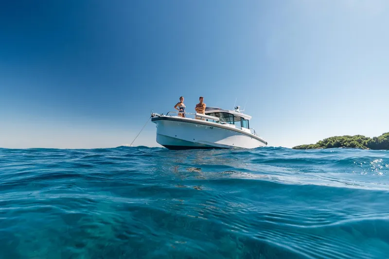 Slide: The Image of 2026 Axopar 29 XC boat on clear blue water, sunny day, two people onboard. - 3