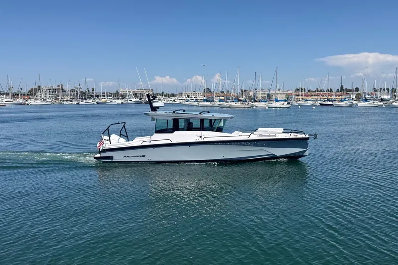 The Image of 2026 Axopar 29 XC Cross Cabin cruising in a marina with sailboats in the background. - 0
