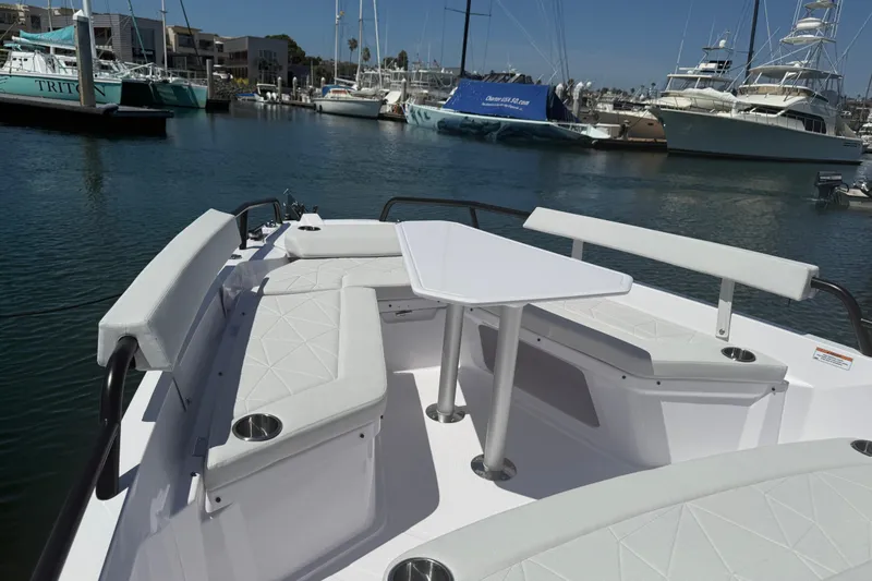Slide: The Image of 2026 Axopar 29 XC Cross Cabin boat with seating and table in a marina. - 13