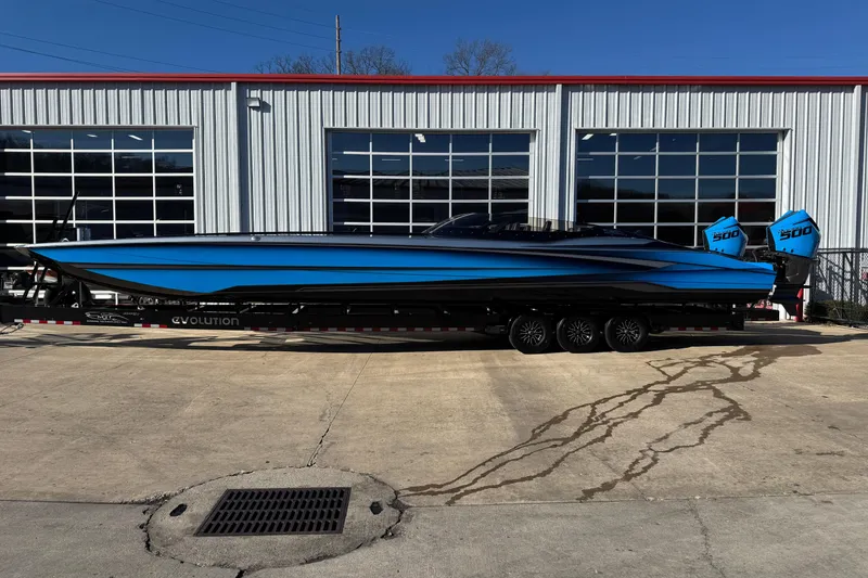 The Image of 2025 MTI 440X boat with blue exterior on a trailer outside a garage. - 0