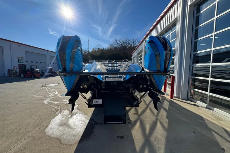 Slide: The Image of Blue MTI 440X boat with dual engines, parked outside a garage, under a sunny sky. - 5