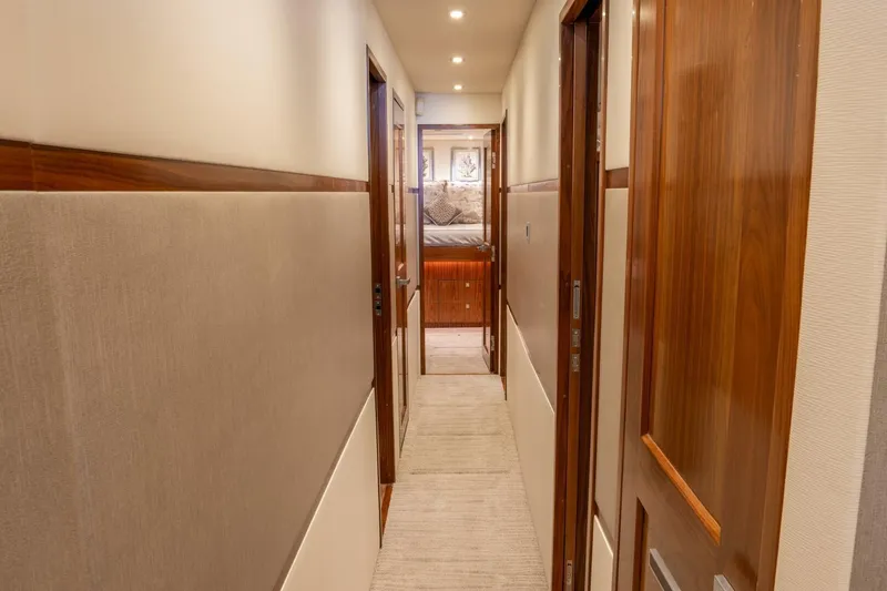 Slide: The Image of Hallway inside 2018 Viking 80 Enclosed Bridge yacht with wooden doors and soft lighting. - 16