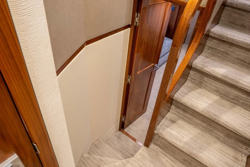 Slide: The Image of Interior of 2018 Viking 80 Enclosed Bridge yacht, featuring wooden door and carpeted stairs. - 17