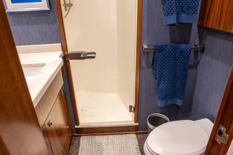 Slide: The Image of Luxurious bathroom in 2018 Viking 80 Enclosed Bridge yacht with shower and blue towels. - 31