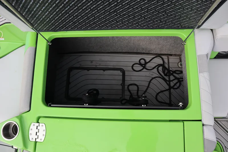 Slide: The Image of Open storage compartment in 2021 Nautique Super Air Nautique G23 boat, featuring green and gray interior. - 25