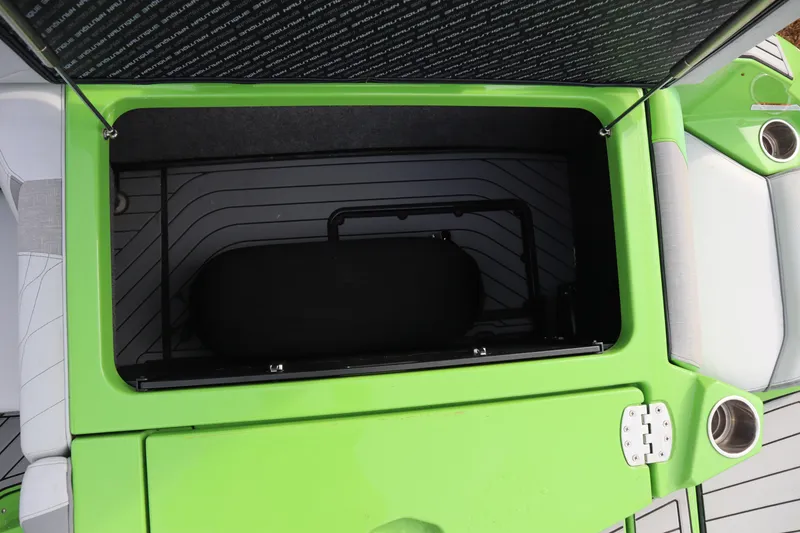 Slide: The Image of Open storage compartment in 2021 Nautique Super Air Nautique G23 boat, featuring green and gray interior. - 27