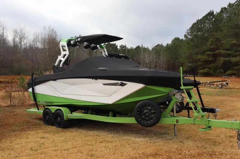 Slide: The Image of 2021 Nautique Super Air Nautique G23 boat on trailer, covered, in grassy area. - 3