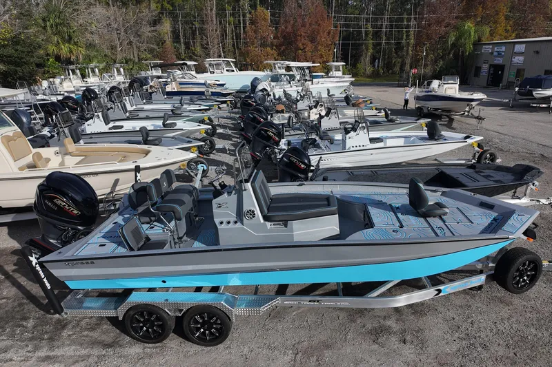 Slide: The Image of 2026 Xpress X23B Bay Lounge boat on trailer, surrounded by other boats in a dealership. - 2