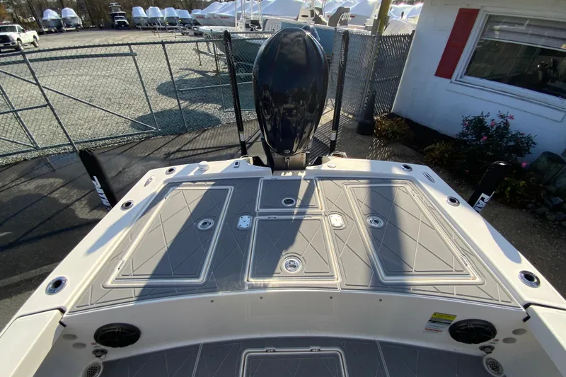 Slide: The Image of 2023 Pathfinder 2300 HPS boat deck with storage compartments and motor, in a marina setting. - 16