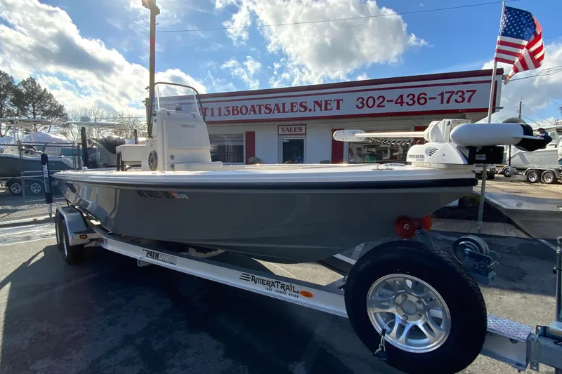 Slide: The Image of 2023 Pathfinder 2300 HPS boat on trailer at dealership, American flag in background. - 3