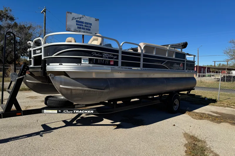 The Image of 2016 Sun Tracker Fishin' Barge 20 DLX pontoon boat on trailer, outdoor setting. - 1