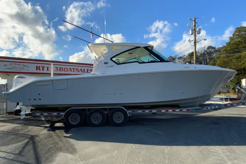 The Image of 2026 Pursuit DC 326 Dual Console boat on trailer at dealership, clear sky background. - 1