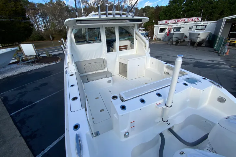 Slide: The Image of 2026 Pursuit DC 326 Dual Console boat at dealership, showcasing spacious deck and seating. - 11