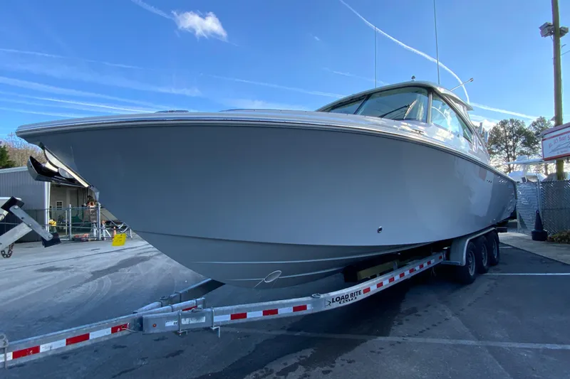 Slide: The Image of 2026 Pursuit DC 326 Dual Console boat on trailer, parked outdoors under clear blue sky. - 5