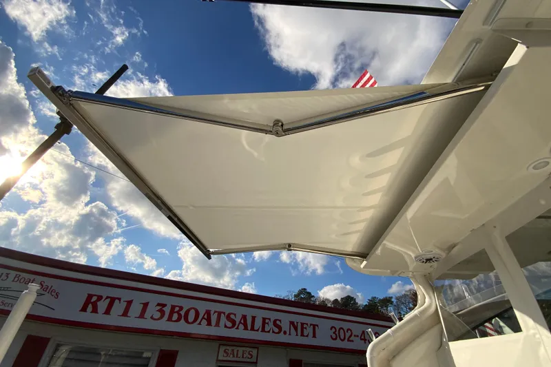 Slide: The Image of 2026 Pursuit DC 326 Dual Console boat with sunshade, blue sky background. - 54